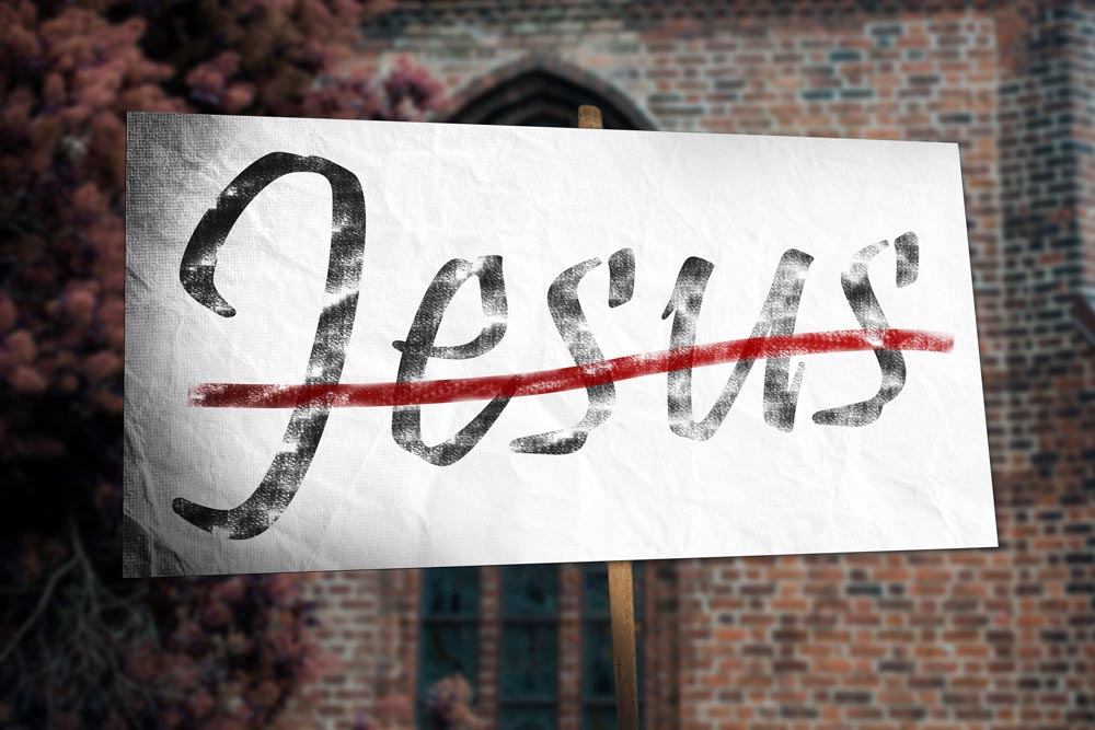 Placard held in front of a church with the word 'Jesus' struck through by a red line..